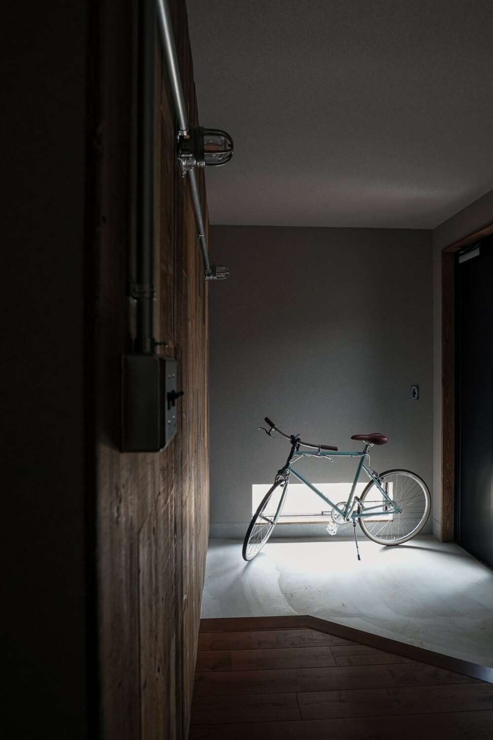 自転車やキャンプ道具が映えるモルタルの玄関土間